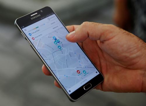 A staff member of nuTonomy demonstrates their self-driving taxi booking app on a mobile phone drives during its public trial in Singapore August 25, 2016. REUTERS/Edgar Su  - D1BETXLELYAA