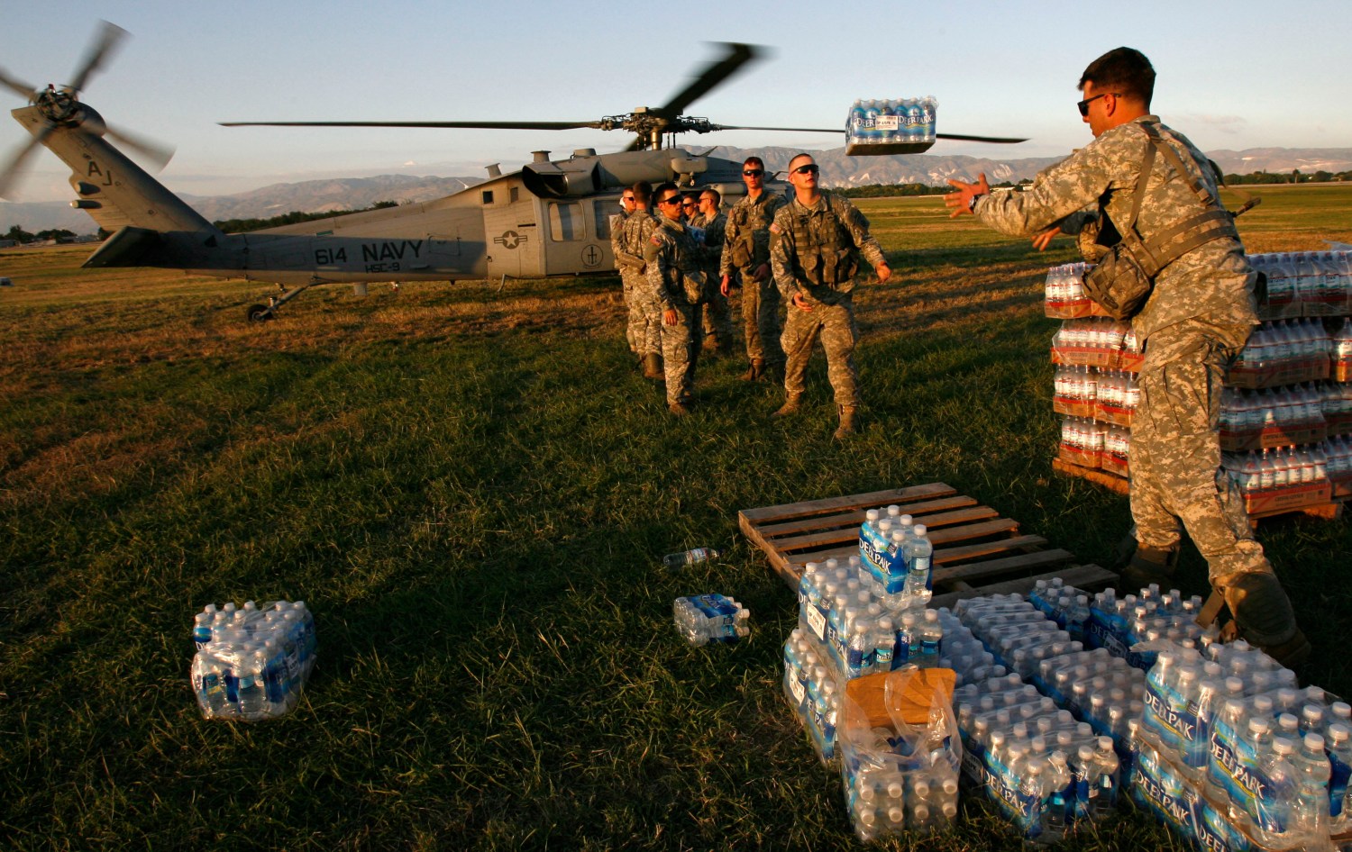 U.S. soldiers of the 82nd Airborne help load water onto a Navy helicopter at a staging area at Port-au-Prince international airport January 17, 2010. Relief efforts continue in the island nation's capital after last week's devastating earthquake. U.S. troops will help U.N. peacekeepers keep order on Haiti's increasingly lawless streets, the country's president said on Sunday as aid workers struggled to get food and medical assistance to desperate earthquake survivors.      REUTERS/Hans Deryk    (HAITI - Tags: DISASTER MILITARY) - GM1E61I0YZK01