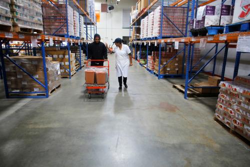 Fritza Lemitelamy (R) and her son Jonathan, students in the Culinary Job Training Program at the New Hampshire Food Bank, cart applesauce made by the class to a freezer amid shelves of the food bank's storage space in Manchester, New Hampshire November 6, 2013.  Fritza Lemitelamy, a single mother of six, and two of her children are taking the eight week course for the unemployed and the underemployed with the ultimate goal of opening their own Haitian restaurant.  The class, which in addition to teaching kitchen and life skills produces meals for three agencies of the New Hampshire Food Bank.  REUTERS/Brian Snyder (UNITED STATES - Tags: SOCIETY POVERTY FOOD) - TM4E9B719LW01