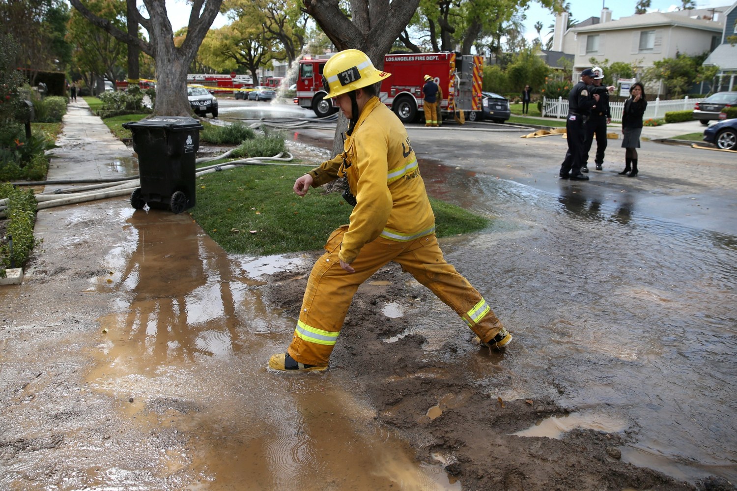 Firefighters work to fix a leak in the water infrastructure beneath the pavement outside a home in Los Angeles, California, U.S., March 22, 2017.  REUTERS/Lucy Nicholson - RC12520EEAE0