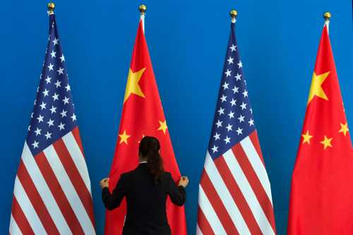 A Chinese woman adjusts a Chinese national flag next to U.S. national flags before a Strategic Dialogue expanded meeting, part of the U.S.-China Strategic and Economic Dialogue (S&ED) held at the Diaoyutai State Guesthouse in Beijing, July 10, 2014. REUTERS/Ng Han Guan/Pool (CHINA - Tags: POLITICS BUSINESS) - GM1EA7A151H01
