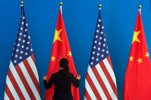 A Chinese woman adjusts a Chinese national flag next to U.S. national flags before a Strategic Dialogue expanded meeting, part of the U.S.-China Strategic and Economic Dialogue (S&ED) held at the Diaoyutai State Guesthouse in Beijing, July 10, 2014. REUTERS/Ng Han Guan/Pool (CHINA - Tags: POLITICS BUSINESS) - GM1EA7A151H01