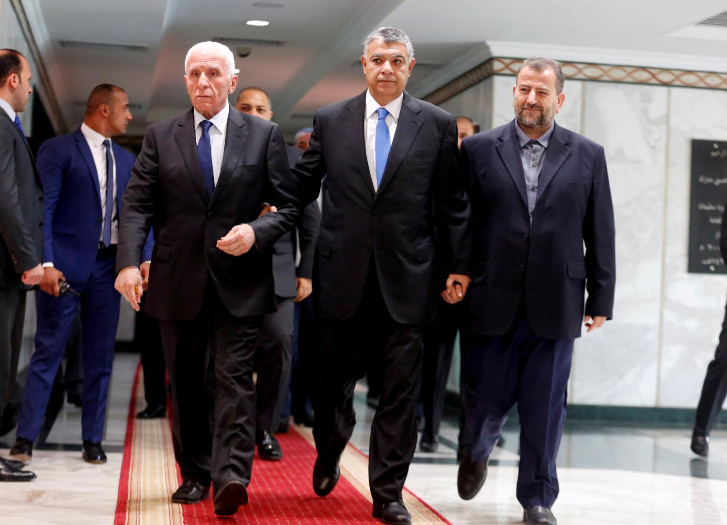 Egyptian intelligence chief Khaled Fawzi (C) walks with head of Hamas delegation Saleh Arouri and Fatah leader Azzam Ahmad as they sign a reconciliation deal in Cairo, Egypt, October 12, 2017. REUTERS/Amr Abdallah Dalsh TPX IMAGES OF THE DAY