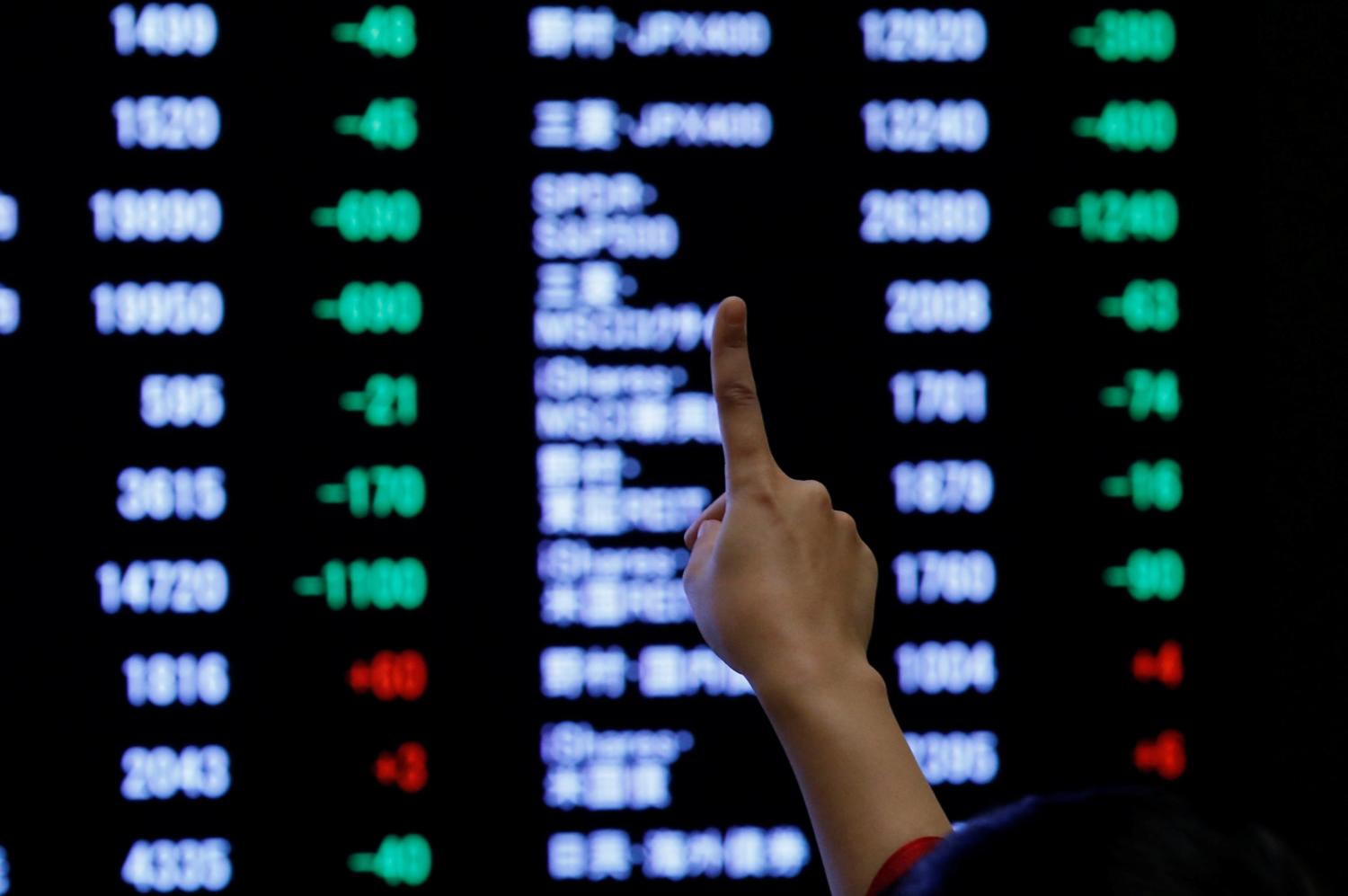 A woman points to an electronic board showing stock prices as she poses in front of the board after the New Year opening ceremony at the Tokyo Stock Exchange (TSE), held to wish for the success of Japan's stock market, in Tokyo, Japan, January 4, 2019. REUTERS/Kim Kyung-Hoon - RC14906C3900