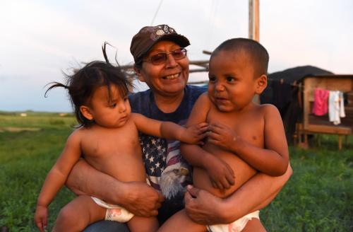 Beatrice Lookinghorse sits with two of her grandchildren, Linda Lookinghorse and Cody James Lookinghorse, in the backyard of her home on the Cheyenne River Reservation in Green Grass, South Dakota, U.S., May 28, 2018. Beatrice Lookinghorse is related to several of the Fort Laramie treaty riders who live with her. Beatrice also raises other children from the extended Lookinghorse family. "I promised my father that none of his grandkids would ever be put in the (foster care) system," she said. REUTERS/Stephanie Keith  SEARCH "KEITH ANNIVERSARY" FOR THIS STORY. SEARCH "WIDER IMAGE" FOR ALL STORIES. - RC1A57AAB7F0