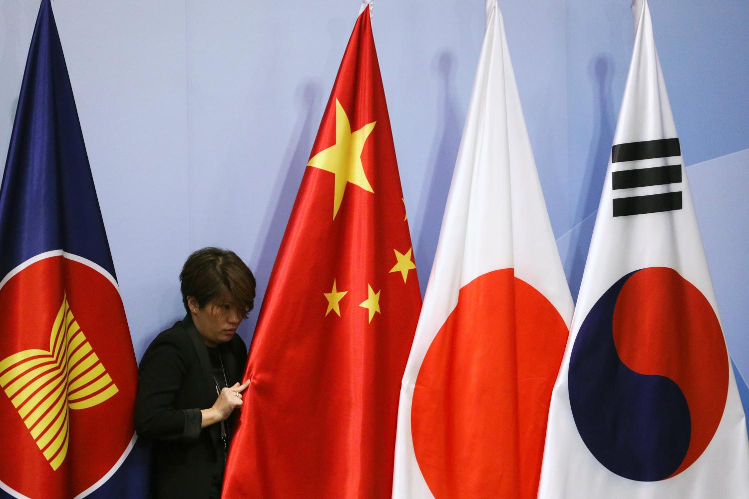 An officer adjusts China's national flag before the ASEAN Plus Three (APT) Summit in Singapore, November 15, 2018. REUTERS/Athit Perawongmetha - RC1C8843E420