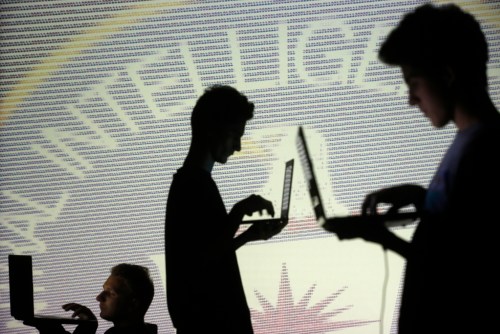 People are silhouetted as they pose with laptops in front of a screen projected with binary code and a Central Inteligence Agency (CIA) emblem, in this picture illustration taken in Zenica October 29, 2014.     REUTERS/Dado Ruvic (BOSNIA AND HERZEGOVINA  - Tags: BUSINESS SCIENCE TECHNOLOGY BUSINESS LOGO)   - LR1EAAT10ZU9I