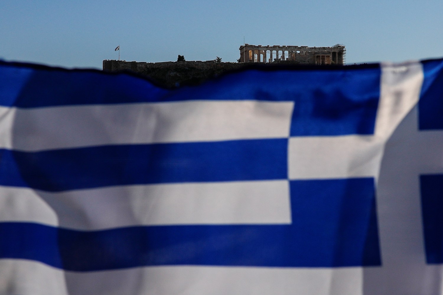 A Greek national flag flutters, as the ancient Parthenon temple is seen atop the Acropolis hill, in Athens, Greece, March 1, 2019. REUTERS/Alkis Konstantinidis - RC1476890910