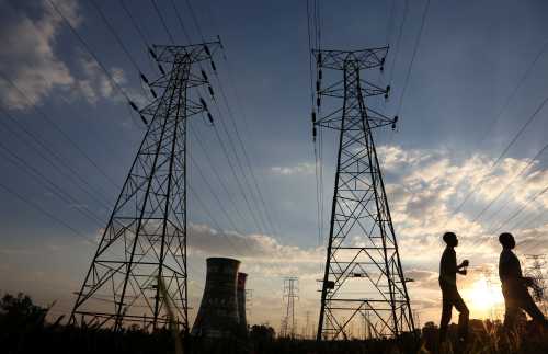 Boys walk past electricity pylons and the cooling towers of the defunct Orlando Power Station in Soweto, South Africa, June 28, 2018. Picture taken June 28, 2018. REUTERS/Siphiwe Sibeko - RC164C8E8250