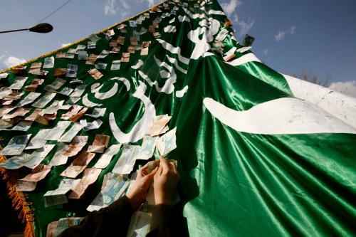 An Iranian man pins banknotes on an Arabic script during the Shi'ite Ashura religious festival in Tehran January 30, 2007. Muslim Shi'ites mark Ashura, the day when Imam al-Hussein, the "leader of the martyrs" and grandson of Prophet Mohammad was killed in Kerbala in 680 AD. REUTERS/Morteza Nikoubazl (IRAN) - GM1DUMRVDQAA