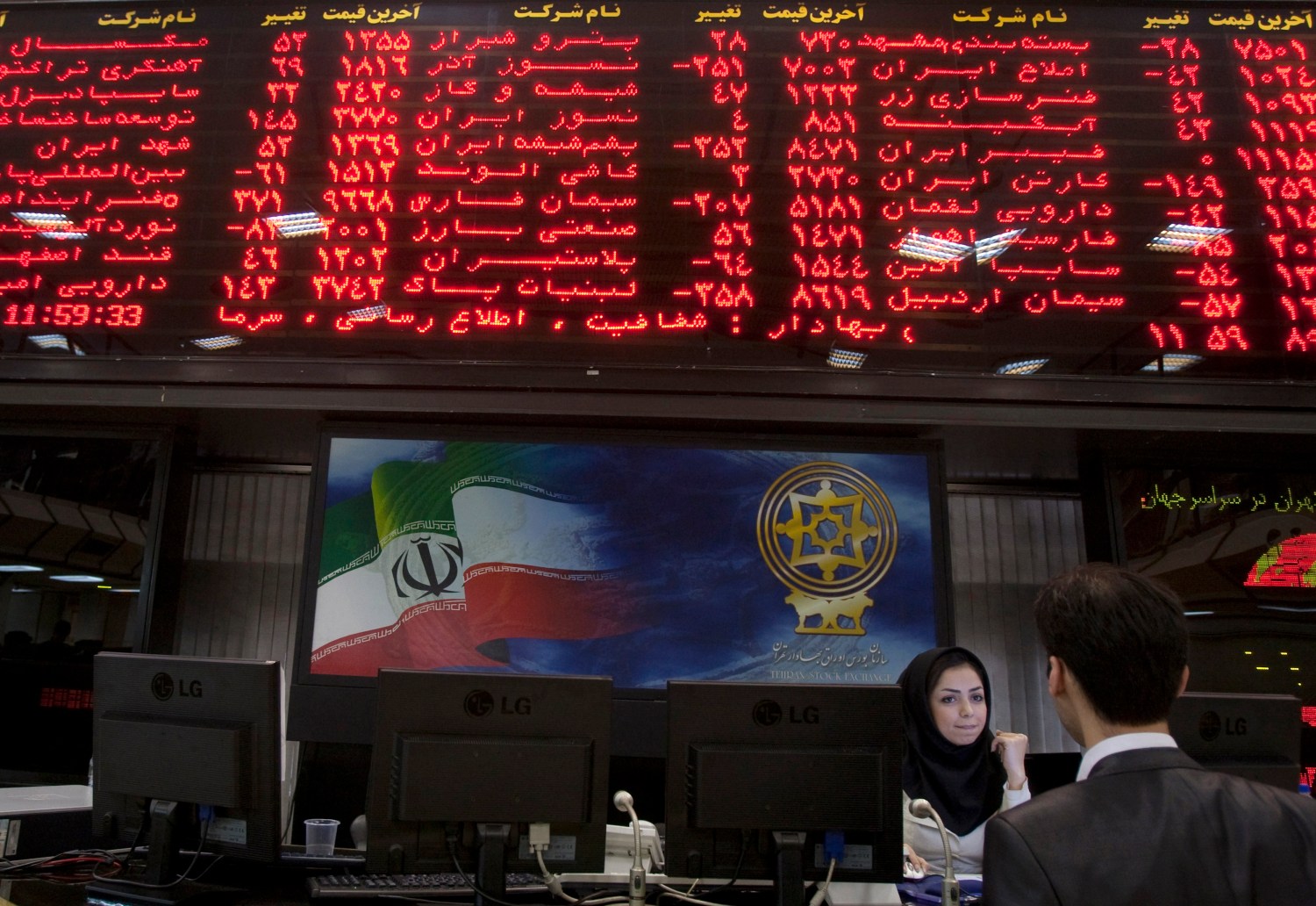 EDITORS' NOTE: Reuters and other foreign media are subject to Iranian restrictions on their ability to report, film or take pictures in Tehran. A trader speaks with a stock market official beneath the electronic board at the Tehran stock exchange September 15, 2010. While U.S. diplomats were busy upping Iran's economic punishment over nuclear activities Washington fears are aimed at making a bomb, Iranian shares, which might have been expected to fall, have, instead, gone through the roof. Picture taken September 15, 2010. To match Feature IRAN-ECONOMY/BOURSE REUTERS/Caren Firouz (IRAN - Tags: BUSINESS) - GM1E69U0R0301