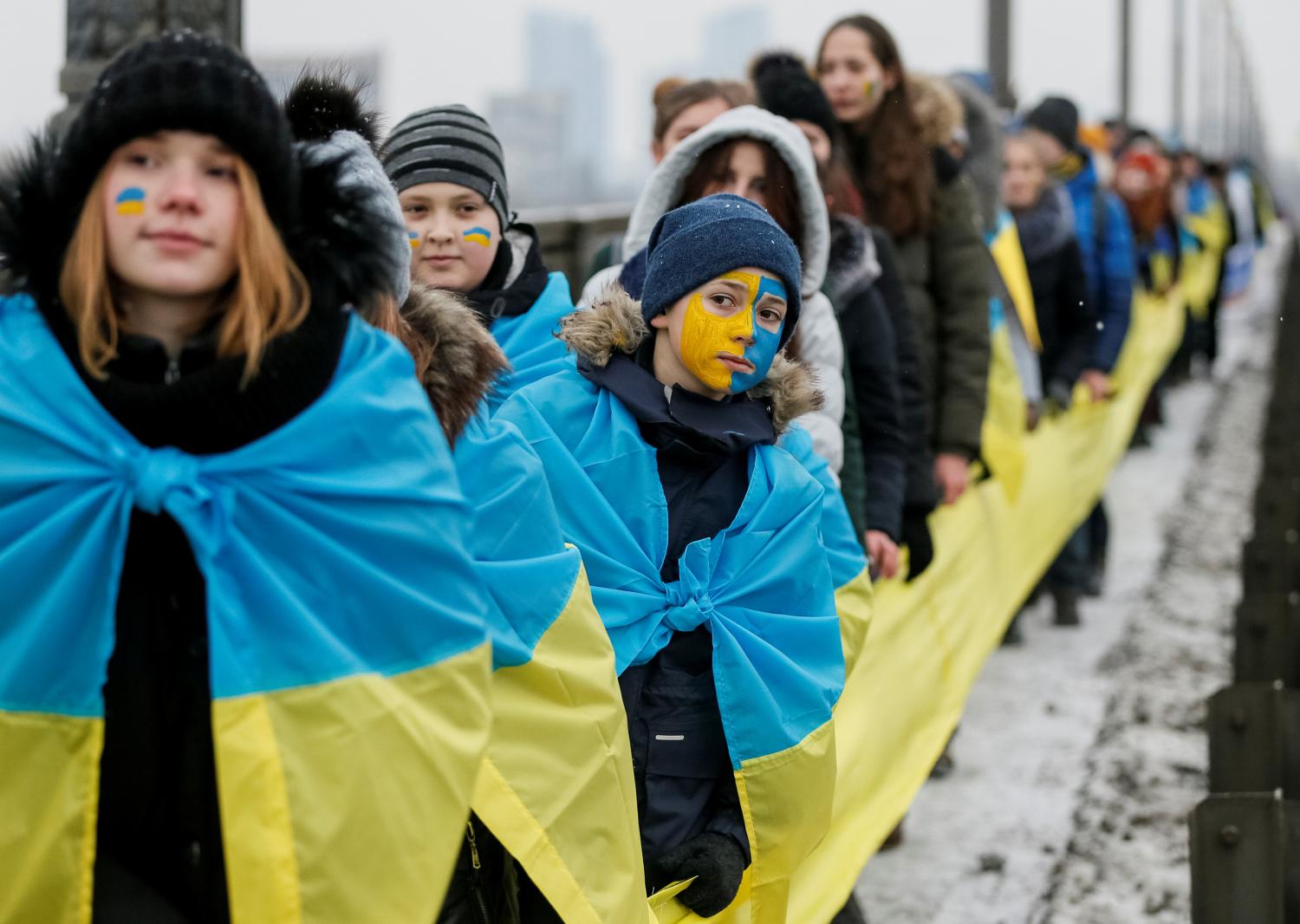 People carry national flags on a bridge while forming a human chain across the Dnipro River during celebrations for Unity Day in Kiev, Ukraine January 22, 2018.  REUTERS/Gleb Garanich - RC17BE5651A0