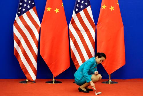 An attendent cleans the carpet next to U.S. and Chinese national flags before a news conference for the 6th round of U.S.-China Strategic and Economic Dialogue at the Great Hall of the People in Beijing, July 10, 2014. REUTERS/Jason Lee (CHINA - Tags: POLITICS BUSINESS) - GM1EA7A1AO901