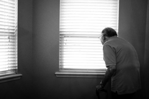 elderly man looks out the window