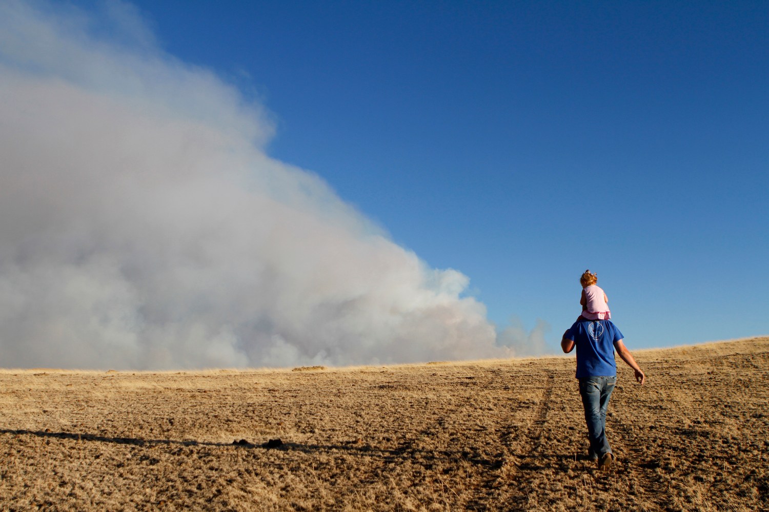 Colt Groff carries his daughter Peyton Groff on his shoulders as they look at the smoke from the Wallow wildfire in Apache County, Arizona June 9, 2011. Forest rangers in eastern Arizona stepped up the attack on the massive wildfire that has displaced as many as 11,000 people, exploiting better weather conditions on Thursday to finally begin curtailing the blaze. REUTERS/Joshua Lott (UNITED STATES - Tags: DISASTER ENVIRONMENT) - GM1E76A0X2801