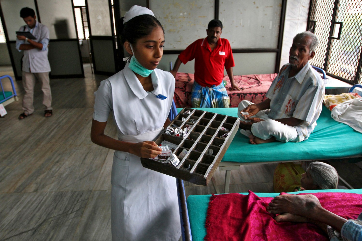 A paramedic distributes free medicine provided by the government to patients inside a ward at Rajiv Gandhi Government General Hospital (RGGGH) in Chennai July 12, 2012. Chennai is the capital of Tamil Nadu, one of two Indian states offering free medicine for all. The state provides a glimpse of the hurdles India faces as it embarks on a programme to extend free drug coverage nationwide. Picture taken July 12, 2012. To match Analysis INDIA-DRUGS/             REUTERS/Babu (INDIA - Tags: HEALTH SOCIETY DRUGS) - GM1E87N0HMY01