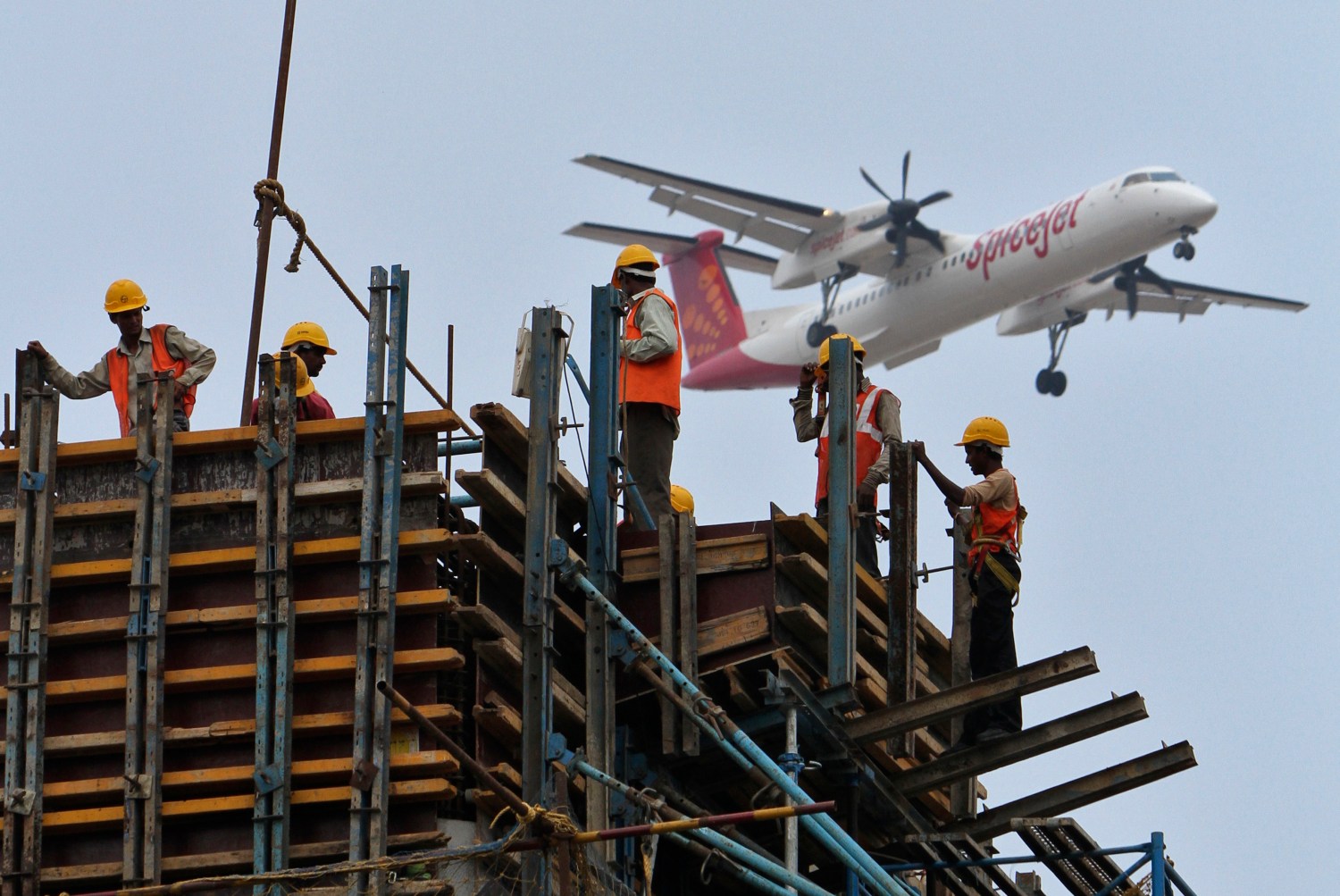 Construction workers erect scaffolding at the site of metro station as a SpiceJet Airlines aircraft flies past in the southern Indian city of Chennai May 14, 2012. Growth in Asia's third-largest economy is slowing as costlier credit and the impact of Europe's debt crisis on exports have sapped expansion. Gross domestic product rose 6.1 percent in December quarter from a year earlier, the slowest pace in near three years. REUTERS/Babu (INDIA - Tags: TRANSPORT BUSINESS CONSTRUCTION) - GM1E85E1KU101