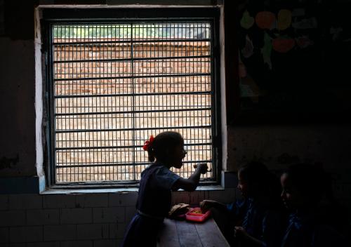 Schoolgirls eat their free mid-day meals, distributed by a government-run primary school, in New Delhi May 8, 2013.