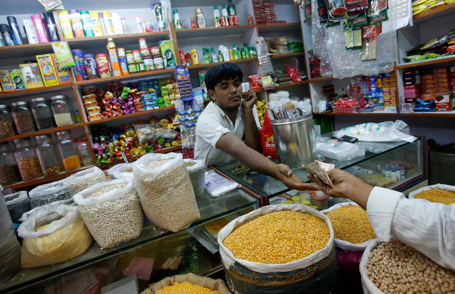 The owner of a "Kirana" or mom-and-pop grocery store accepts money from a customer in his shop in Mumbai December 7, 2012. The Indian government won a second parliament vote on Friday on allowing foreign supermarkets into the country, paving the way for Prime Minister Manmohan Singh to press ahead with more reforms, including freeing up a cash-strapped insurance sector. REUTERS/Vivek Prakash (INDIA - Tags: BUSINESS FOOD) - GM1E8C71Q3R01