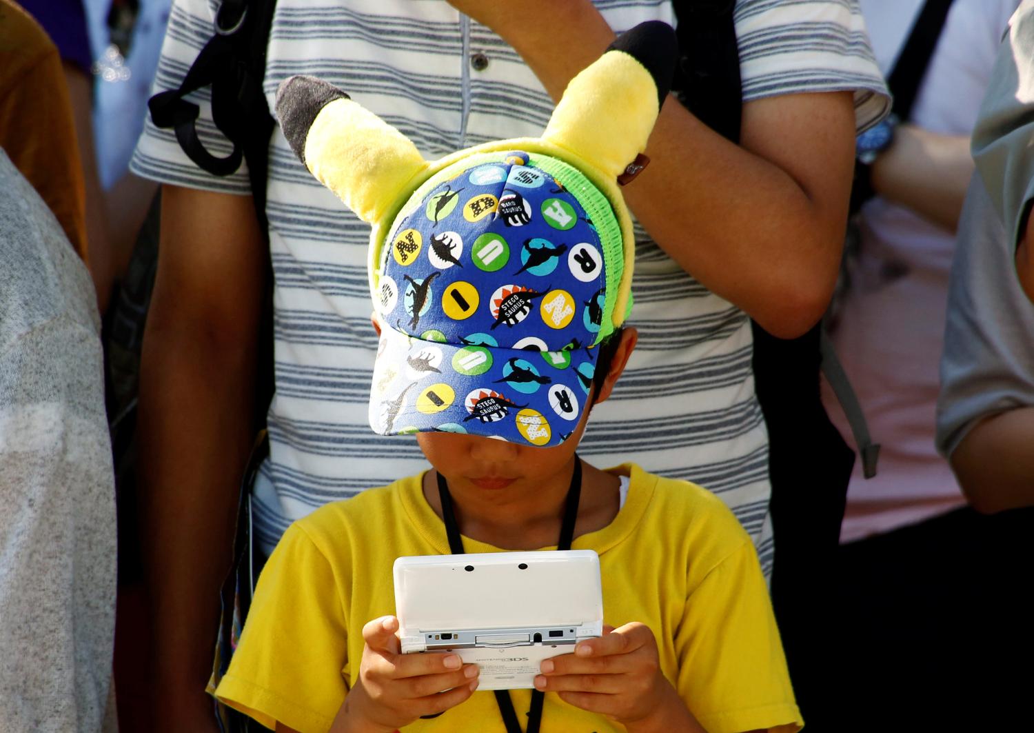 A boy plays Nintendo's game console prior to a parade where Pokemon's character Pikachu attends, in Yokohama, Japan, August 7, 2016. Picture taken on August 7, 2016. REUTERS/Kim Kyung-Hoon - S1AEUJDOXRAB