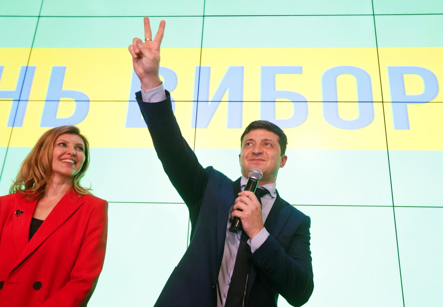 Ukrainian comic actor and presidential candidate Volodymyr Zelenskiy flashes a victory sign as his wife Olena reacts following the announcement of the first exit poll in a presidential election at his campaign headquarters in Kiev, Ukraine March 31, 2019. REUTERS/Valentyn Ogirenko - RC1FE0F095A0