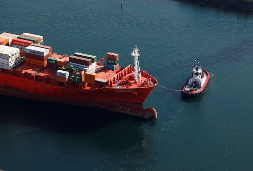 An aerial photo shows one of a pair of tugboats escorting the Cap Jackson container ship, registered in Singapore, at Harbor Island at the Port of Seattle in Seattle, Washington, U.S.