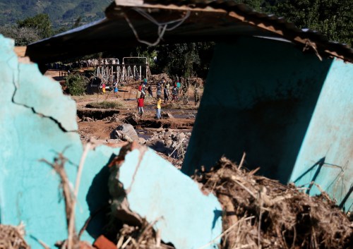 Survivors of cyclone Idai are seen through a destroyed building as they gather to receive aid at Coppa business center in Chipinge, Zimbabwe, March 25, 2019. Picture taken March 25, 2019. REUTERS/Philimon Bulawayo - RC1AFE44B330