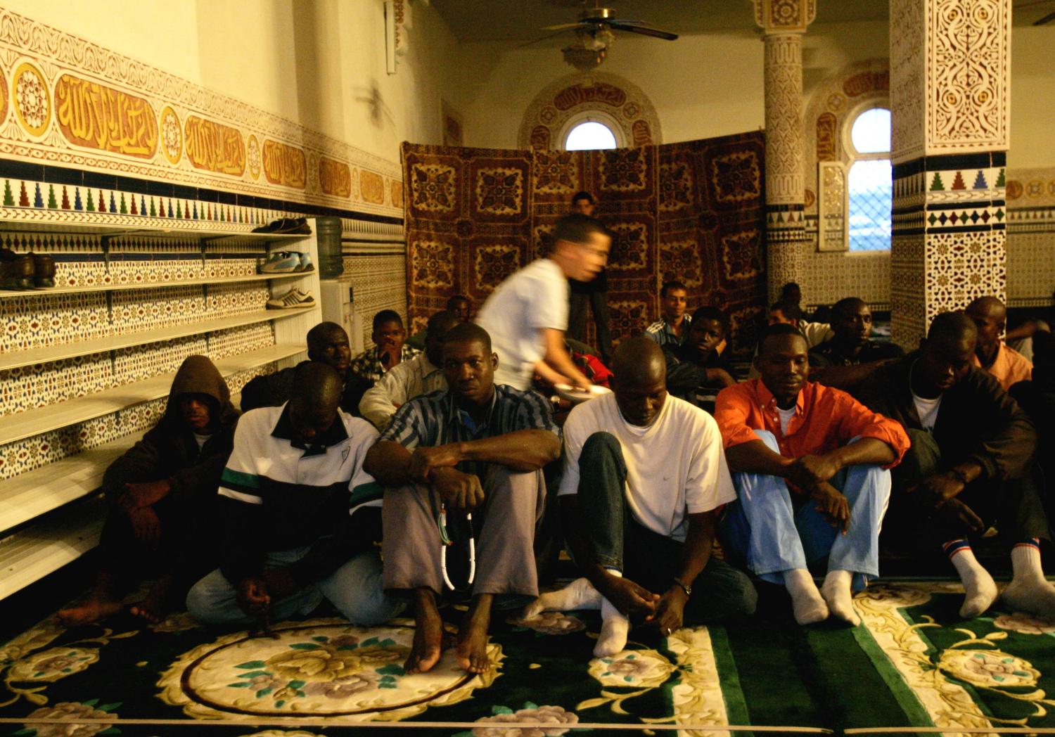 African would-be immigrants (front) pray inside a mosque near the CETI (Short-stay Immigrant Centre) during the fasting month of Ramadan in Spain's North African enclave of Melilla October 10, 2005. Morocco, under pressure to stem illegal immigration to Spain and accused by rights groups of mistreating migrants, began flying detained Africans to Senegal and Mali on Monday, government officials said. 'We have already flown 140 illegal migrants back home in Senegal this morning and we are preparing a flight of 140 others also to Senegal soon from Oujda,' a senior official told Reuters. REUTERS/Andrea Comas - RP2DSFIXLEAB