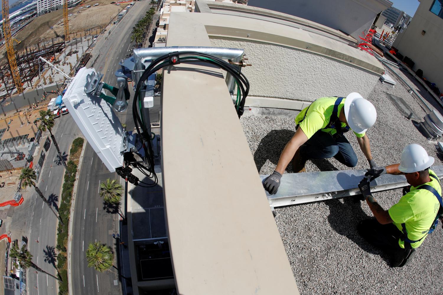 Telecommunications workers Chris Viens and Guy Glover install a new 5G antenna system made by Ericsson for AT&T's 5G wireless network in downtown San Diego, California, U.S., April 23, 2019. Picture taken with a fish eye lens. REUTERS/Mike Blake - RC1BDEA71CE0
