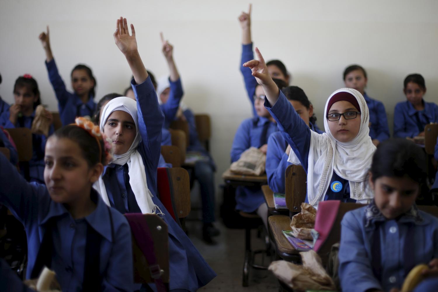 Students raise their hands as they attend class and eat a meal distributed as part of a World Food Programme (WFP)-run project to provide healthy meals to students and to raise awareness of good eating habits, at Hofa Al-Mazar school in the city of Irbid, Jordan, April 26, 2016. REUTERS/ Muhammad Hamed - GF10000396485