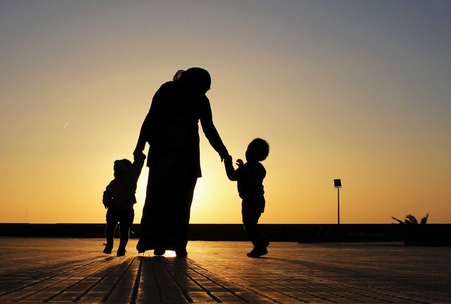 A woman walks with her two children at sunset near the seashore in Benghazi April 29, 2014. REUTERS/Esam Omran Al-Fetori (LIBYA - Tags: SOCIETY) - GM1EA4U0HMU01