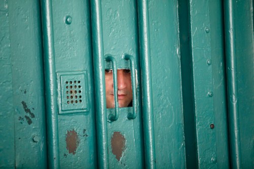A prison guard looks through a small window at the El Harrach prison in Algiers July 14, 2010. Algeria is ready to open its prisons to international inspection to counter allegations that inmates are abused, Farouk Ksentini, chairman of the National Consultative Commission for the Promotion and Protection of Human Rights, a government-backed human rights body, said on Wednesday.       To match Interview ALGERIA-PRISONS/     REUTERS/Louafi Larbi (ALGERIA - Tags: CRIME LAW) - GM1E67F02LF01