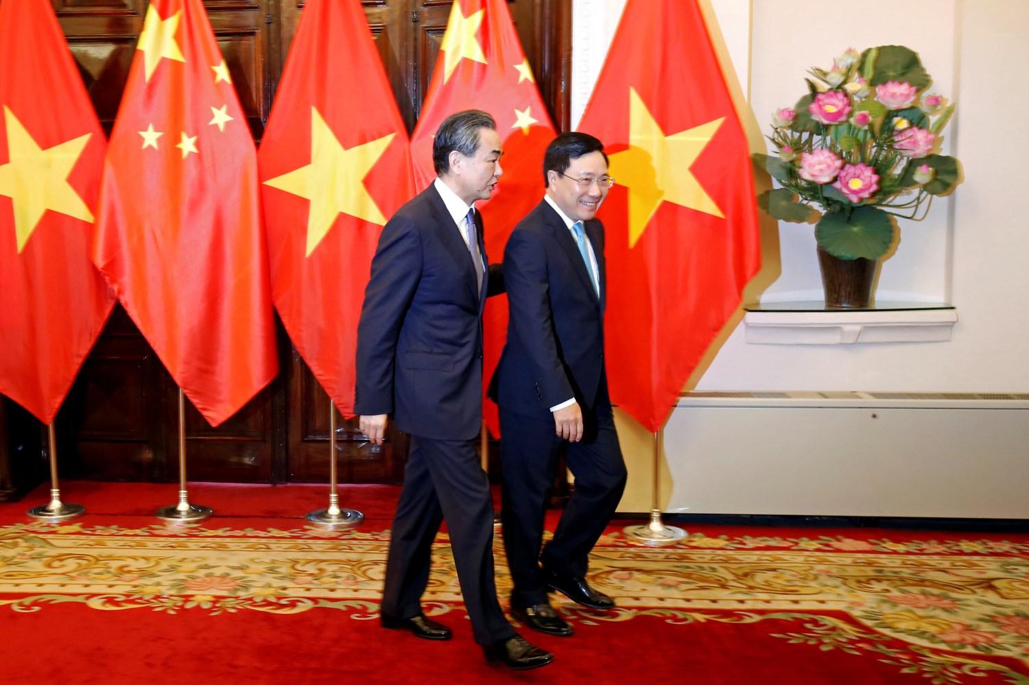 China's State Councilor and Foreign Minister Wang Yi (L) and Vietnam's Deputy Prime Minister and Foreign Minister Pham Binh Minh walk to a meeting room at the Government Guesthouse in Hanoi, Vietnam April 1, 2018. REUTERS/Kham - RC142FA2A510