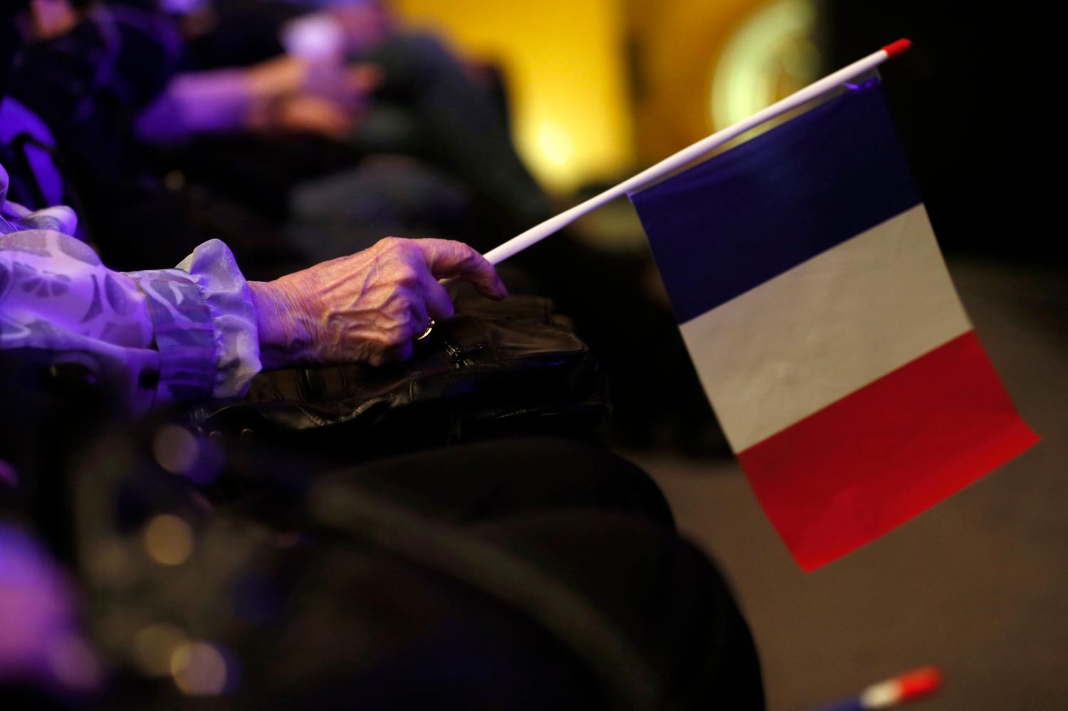 A far-right National Front political party supporter holds a French flag during a rally for local elections in Marseille, March 16, 2014. Registered voters will receive an envelope containing the declarations of faith of candidates for the first turn of the French local elections which will run on March 23. REUTERS/Jean-Paul Pelissier (FRANCE - Tags: POLITICS ELECTIONS) - GM1EA3H08Q901