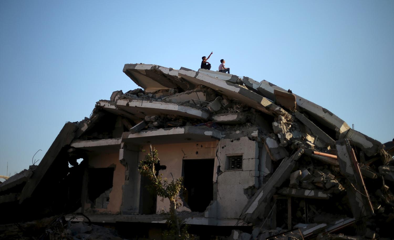 Palestinian boys sit atop the ruins of a house that witnesses said was destroyed by Israeli shelling during a 50-day war last summer, in the east of Gaza City May 12, 2015. REUTERS/Mohammed Salem       TPX IMAGES OF THE DAY      - GF10000092322