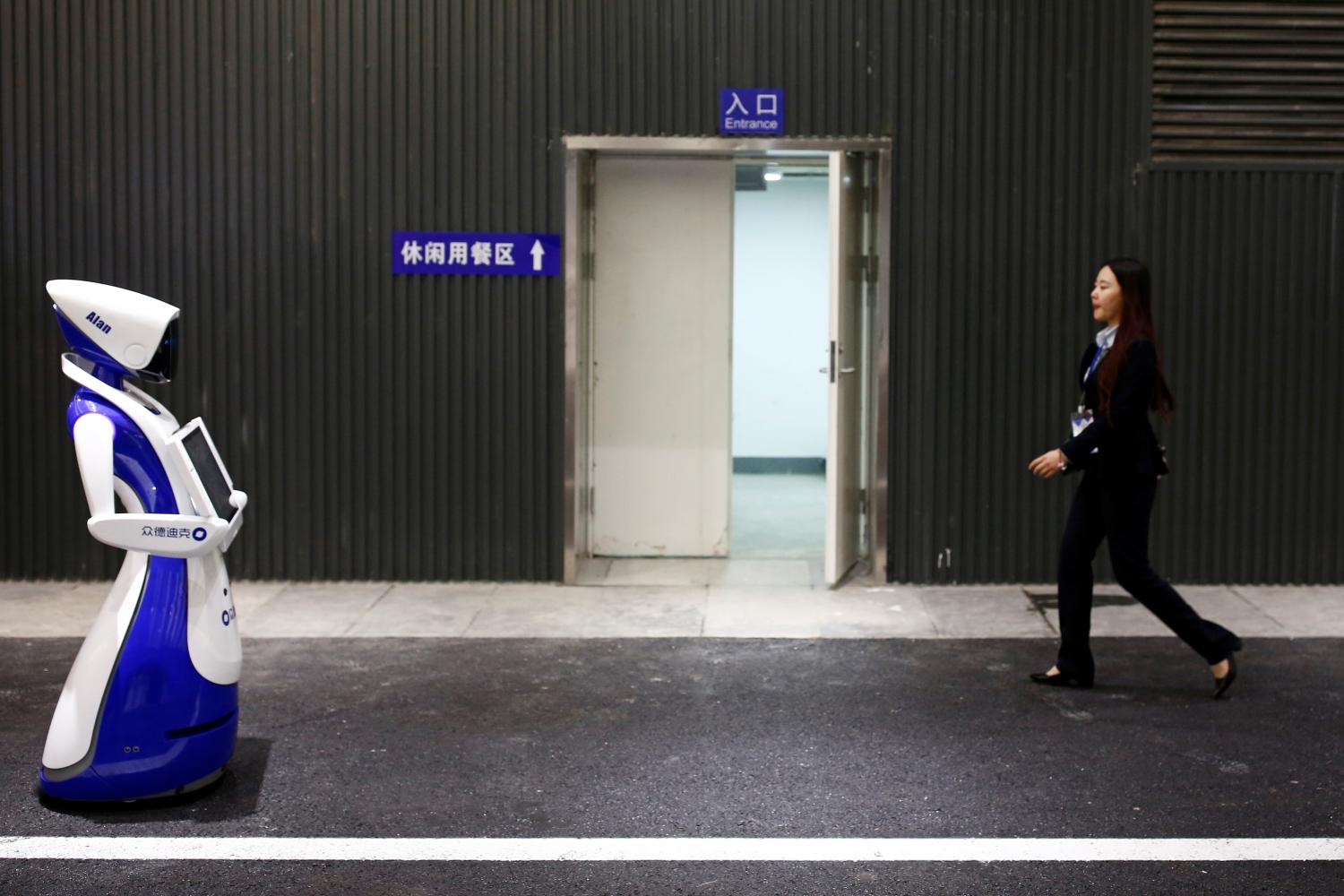 A woman walks past a robot by Robot4U Tech at the WRC 2016 World Robot Conference in Beijing, China, October 21, 2016. REUTERS/Thomas Peter - D1BEUIFGQCAA
