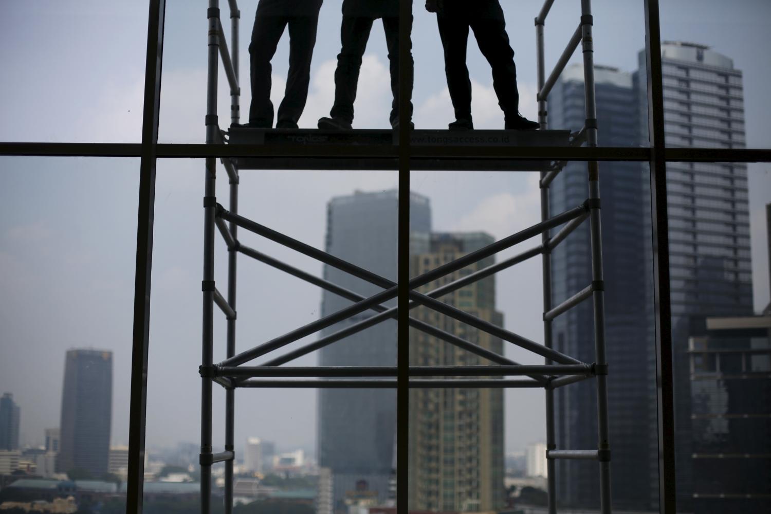 Workers stand on a ladder at a new condominium construction in Jakarta's business district June 11, 2015.   Indonesian property shares all rose in October when it became clear that reform-minded Joko Widodo would be president, but as Southeast Asia's biggest economy charts a weaker course this year, stock investors are keen to separate the wheat from the chaff. Picture taken June 11, 2015. REUTERS/Beawiharta - GF10000124918