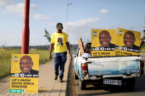 Musa Masina looks at election posters with the face of ANC president Cyril Ramaphosa, before hanging them on street poles in Soweto, South Africa, March 12, 2019. REUTERS/Siphiwe Sibeko - RC1E91576A50