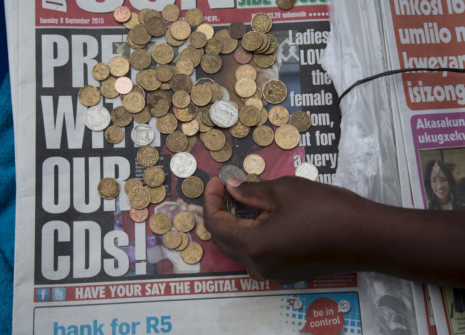 A newspaper vendor counts out change for a customer in Durban, September 8, 2015. South Africa's rand firmed more than 1 percent against the dollar, recovering from record lows in the previous session as bets on a rate hike in United States faded due to worries over global growth. The rand rose 1.04 percent to 13.8150 per dollar. REUTERS/Rogan Ward - GF10000197505