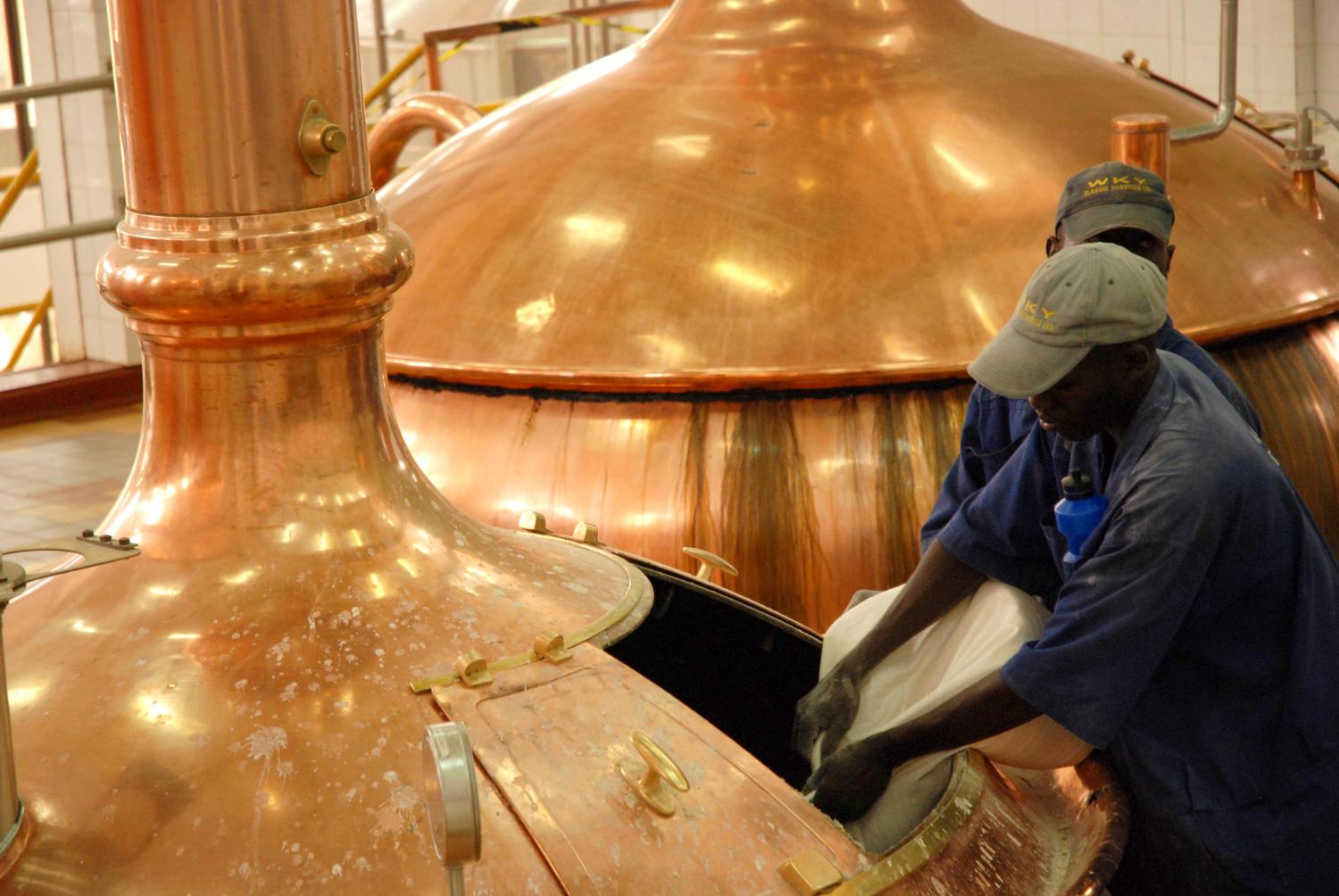 Workers pour brewing ingredients in a copper kettle at the Nile Brewery Company, 76 kilometres (46 miles) east of Uganda's capital Kampala, March 31, 2009. Big brewers operating in Africa may be slower to dismiss the threat from the global economic crisis that has caused economic havoc in the Democratic Republic of Congo and elsewhere. Some brewers report a slowdown in sales growth, but they say Africa nevertheless offers rich expansion prospects compared with elsewhere, and even reduced growth on the continent will outstrip that of other regions this year.  Picture taken March 31, 2009. To match feature BEER-AFRICA/  REUTERS/James Akena (UGANDA BUSINESS FOOD DRINK) - GM1E54H0PQE01