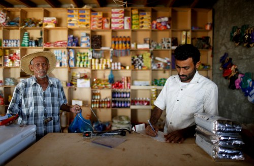 A customer stands by as a vendor calculates at a shop near the village of al-Jaraib, in the northwestern province of Hajjah, Yemen, February 20, 2019. REUTERS/Khaled Abdullah     SEARCH "YEMEN HUNGER" FOR THIS STORY. SEARCH "WIDER IMAGE" FOR ALL STORIES. - RC18893184D0