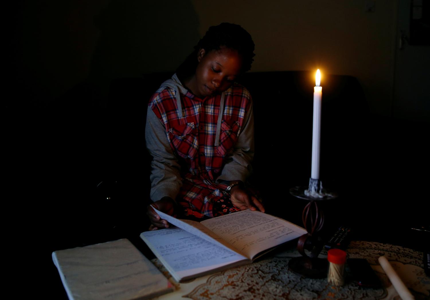 Student Rutendo Madziva reads by candlelight during an electrical power cut in Marondera, Zimbabwe, May 14, 2019. Picture taken May 14, 2019.REUTERS/Philimon Bulawayo - RC1F73894D30