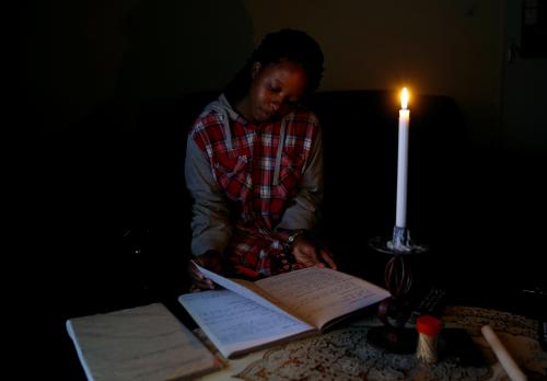 Student Rutendo Madziva reads by candlelight during an electrical power cut in Marondera, Zimbabwe, May 14, 2019. Picture taken May 14, 2019.REUTERS/Philimon Bulawayo - RC1F73894D30