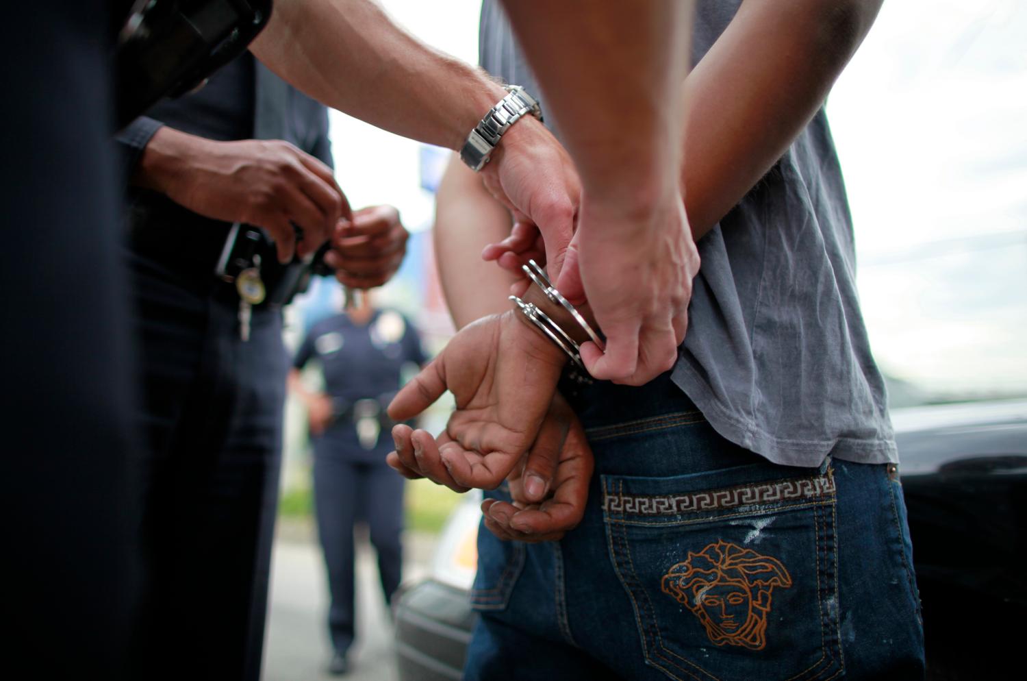 Officers arrest a man suspected of stealing his girlfriend's car in south Los Angeles, California, April 25, 2012. This April 29 will mark the 20th anniversary of the Los Angeles Riots following the acquittal of four Los Angeles police officers in the videotaped beating of motorist Rodney King. The 77th division of south Los Angeles, where the riots began, is an 11.2 square mile area. It has seen a drop from 162 homicides 20 years ago, to 16 so far this year. There are around 34 gangs operating in the division. REUTERS/Lucy Nicholson (UNITED STATES - Tags: CRIME LAW CIVIL UNREST) - GM1E84Q16O501