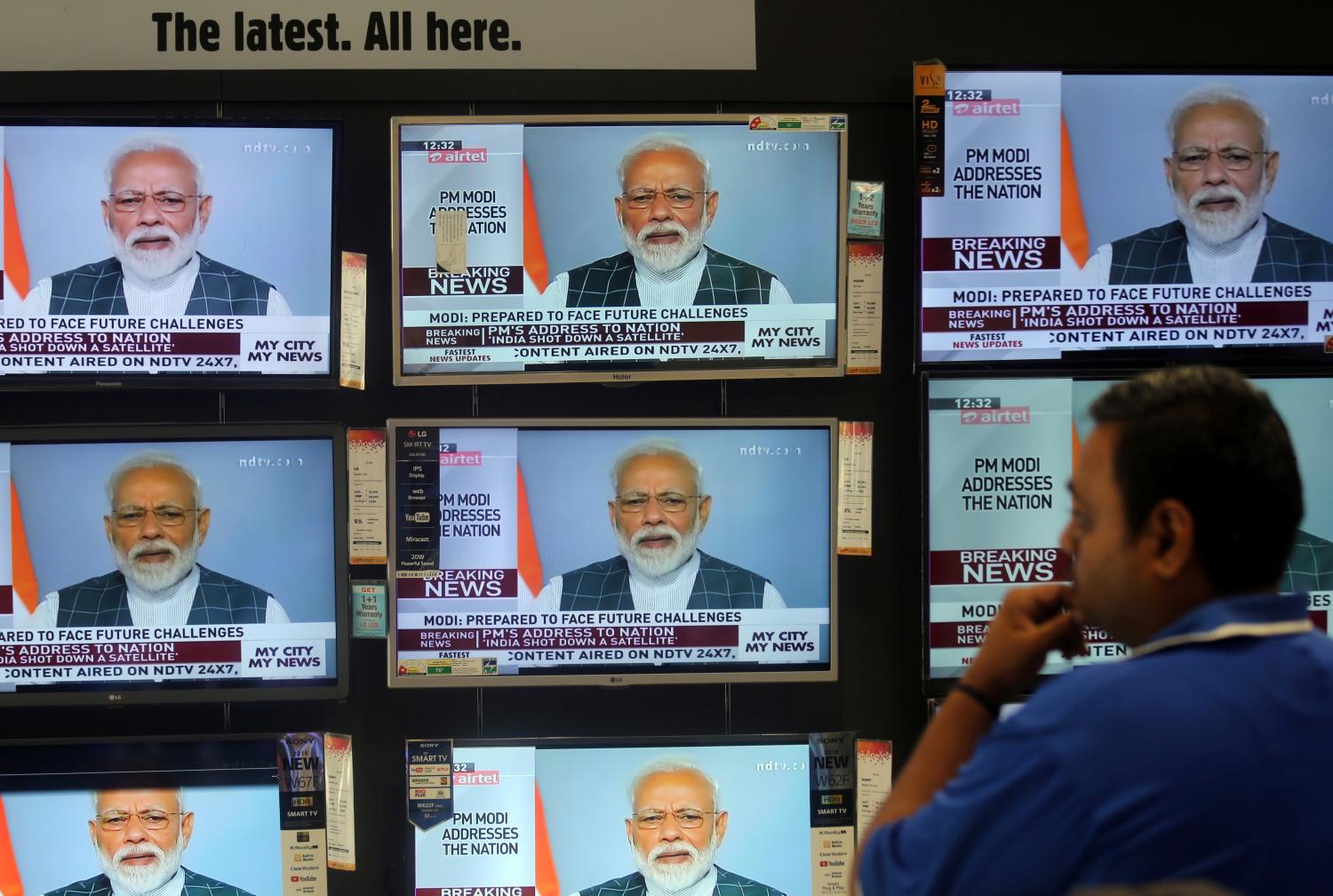 A man watches Prime Minister Narendra Modi addressing to the nation, on TV screens inside a showroom in Mumbai, India, March 27, 2019. REUTERS/Francis Mascarenhas - RC1B207CBD20