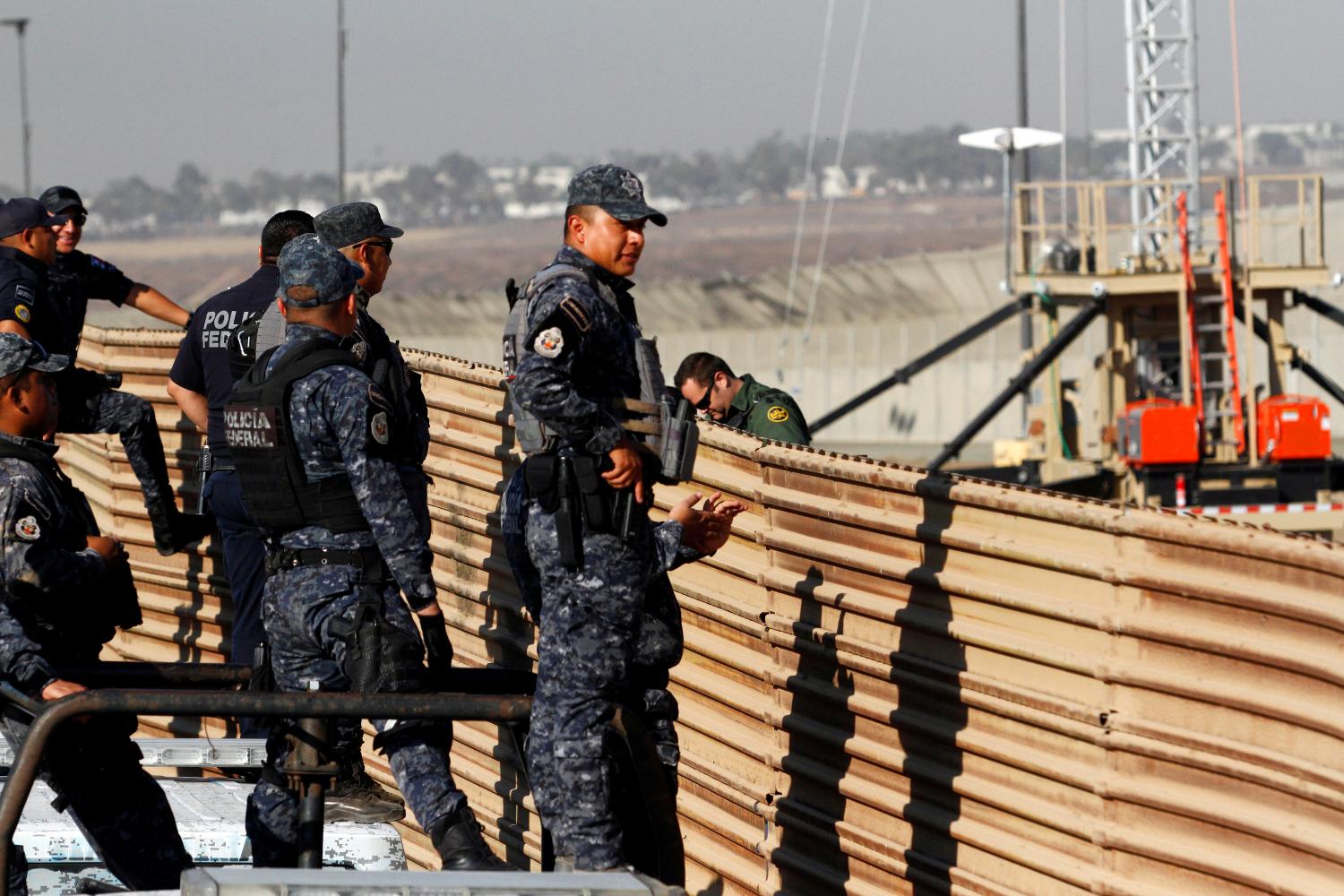 Mexican federal police officers look over the current border fence, while U.S. border patrol authorities (not pictured) visit the site where several prototypes for U.S. President Donald Trump's border wall with Mexico have been built, in this picture taken from the Mexican side of the border, in Tijuana, Mexico, October 26, 2017. REUTERS/Jorge Duenes - RC1DEABF0E80