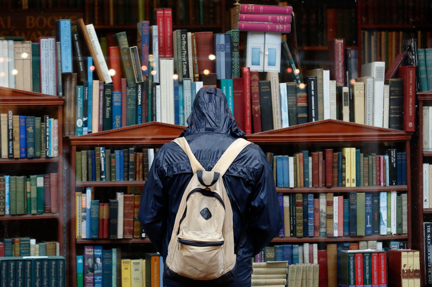 A man stands in the rain looking into the window of an antiquarian book seller in Brighton, southern England January 8, 2015.  British businesses enjoyed a strong end to 2014, marked by rising demand at home and abroad and a record number of companies hiring staff, a major business survey showed on Thursday.  REUTERS/Luke MacGregor  (BRITAIN - Tags: BUSINESS ENVIRONMENT) - LM1EB1813YC01