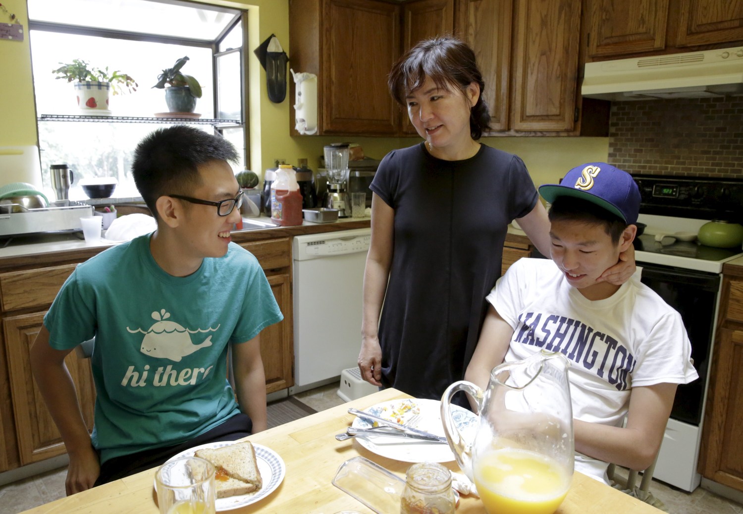 Un Bang (C) spends time with her sons, Shane Bang (L), 21, and Simon Bang (R), 18, at their home in Federal Way, Washington August 8, 2015. With his parents out of work and an office job paying his bills, college junior Shane remembers the anxiety he felt when his younger brother told his family he was headed to University of Washington in the fall. Then they got an unexpected lifeline. A law that took effect last month slashed tuition at public colleges and universities over the next two academic years as much as 20 percent for all Washington students, rich and poor alike. Picture taken August 8, 2015. To match Feature USA-EDUCATION/WASHINGTON      REUTERS/Jason Redmond - GF20000019465