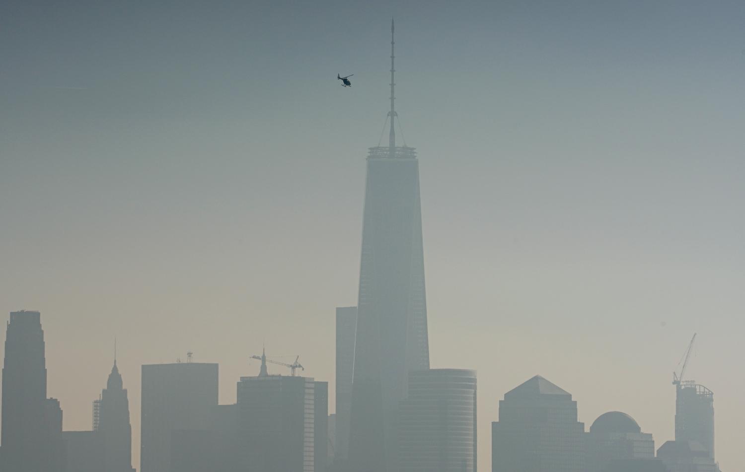 A helicopter flies over the Hudson River with One World Trade Center and Lower Manhattan in the background, on a hazy day in New York City, December 6, 2015. REUTERS/Rickey Rogers      TPX IMAGES OF THE DAY         - GF10000256860