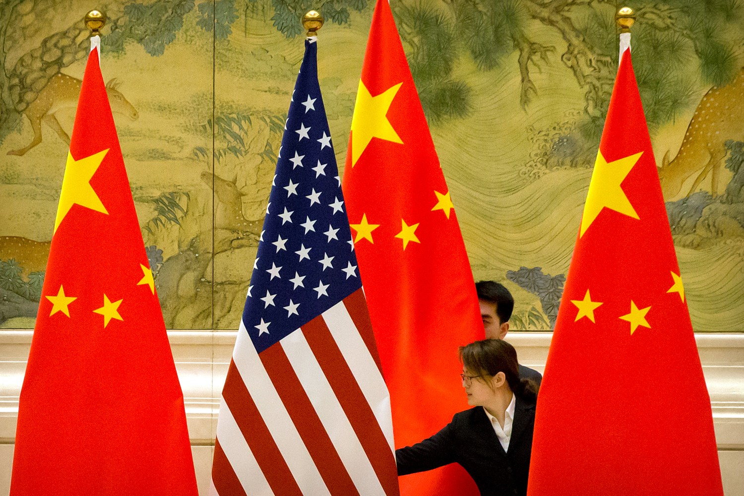 Chinese staffers adjust U.S. and Chinese flags before the opening session of trade negotiations between U.S. and Chinese trade representatives at the Diaoyutai State Guesthouse in Beijing, Thursday, Feb. 14, 2019. Mark Schiefelbein/Pool via REUTERS - RC16D7D1C040